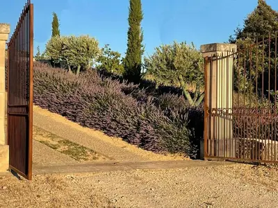 an open gate in a garden with purple bushes at Villa Abayers in Apt
