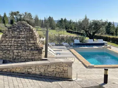 a swimming pool with a stone wall next to a stone fireplace at Villa Abayers in Apt