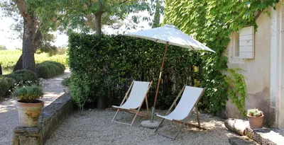two chairs and an umbrella in a yard at Domaine Faverot in Maubec