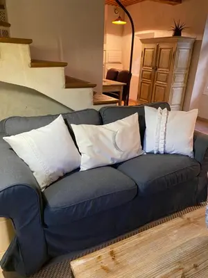 a blue couch with white pillows in a living room at Domaine Faverot in Maubec