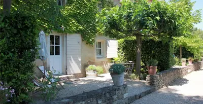 a small house with a stone wall and potted plants at Domaine Faverot in Maubec