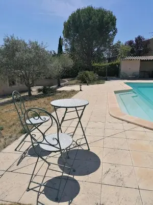 a table and chair sitting next to a swimming pool at Maison au calme entre vignes et Luberon in La Motte-dʼAigues