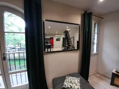 a mirror in a room next to a window at Le Loft sur les quais in LʼIsle-sur-la-Sorgue