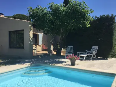 a swimming pool with two chairs and a tree at Petit cocon dans le Luberon in Lauris