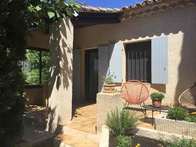 a patio with a red chair in front of a house at Petit cocon dans le Luberon in Lauris
