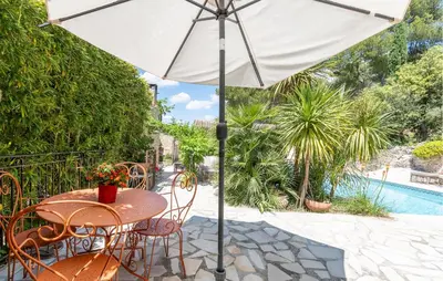 a table and chairs with an umbrella on a patio at Amazing Home In Orgon in Orgon