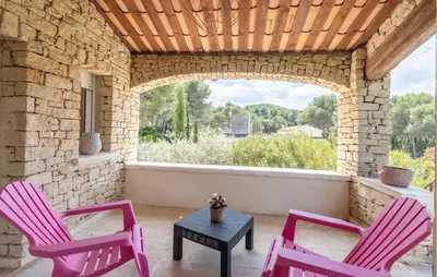 two pink chairs and a table on a patio at Amazing Home In Orgon in Orgon