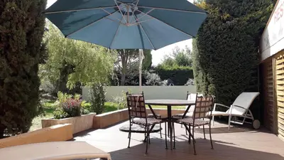 a table and chairs with a blue umbrella on a patio at Le Mas Du Colombier in Cadenet