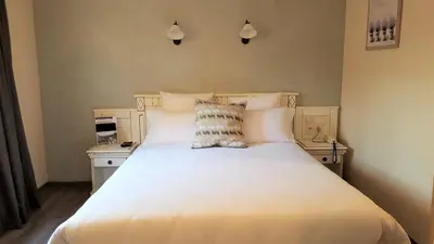 a bedroom with a large bed with white sheets and pillows at Le Mas Du Colombier in Cadenet