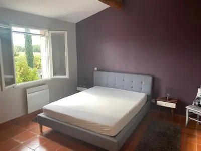 a bedroom with a white bed with a window at Villa Les Oliviers in Caromb