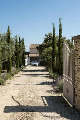 a driveway with a fence and a car parked on the road at Villa Les Oliviers in Caromb