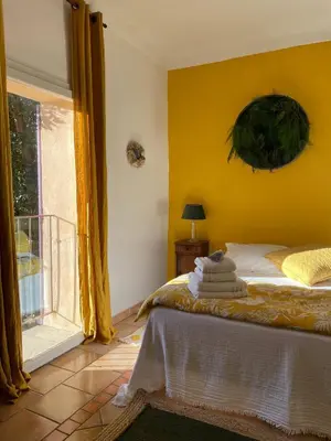 a bedroom with a bed with yellow walls and a window at Mas de la Sacristière in Jonquerettes