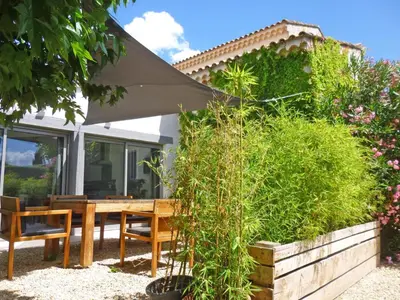 a patio with a table and chairs and an umbrella at Les Platanes in LʼIsle-sur-la-Sorgue
