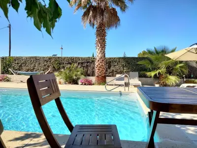 a table and a chair next to a swimming pool at Les Platanes in LʼIsle-sur-la-Sorgue