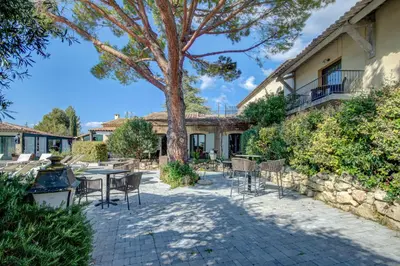a patio with tables and chairs and a tree at Hotel Bastide & SPA - Villa de Lourmarin in Lourmarin