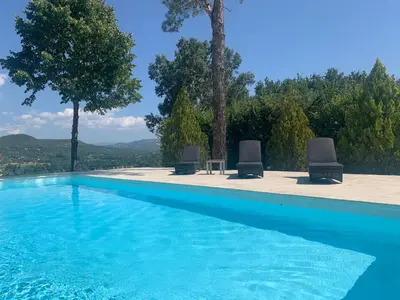 a pool with two chairs and a table and trees at Villa du defens in Saint-Martin-de-Castillon