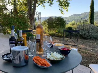 a table with wine bottles and bowls of food at Villa du defens in Saint-Martin-de-Castillon