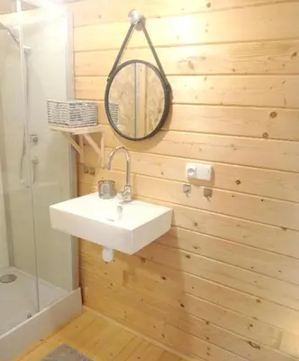 a bathroom with a sink and a mirror on a wooden wall at Charmant chalet à Cornillon-Confoux avec piscine partagée in Cornillon-Confoux