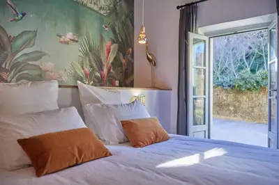 a bed with white pillows and a sliding glass door at Le Clos des Merveilles in Rognes