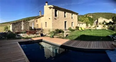 a house with a swimming pool in front of a house at Gîte Coquelicots in Montsalier