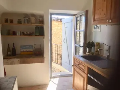 a kitchen with a sink and a door to a patio at Gîte Coquelicots in Montsalier