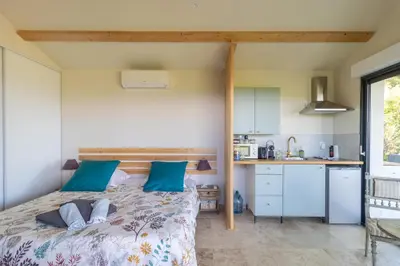 a bedroom with a bed with blue pillows and a kitchen at Terre Luberon in Pertuis