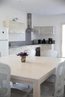 a white kitchen with a table and white chairs at Entre blé et lavande in Bonnieux