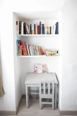 a white table and a chair next to a shelf with books at Entre blé et lavande in Bonnieux