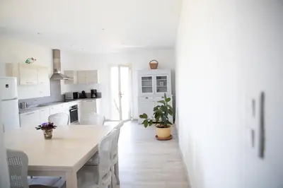 a white kitchen with a wooden table and chairs at Entre blé et lavande in Bonnieux