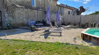 a patio with a pool and two chairs and umbrellas at Entre blé et lavande in Bonnieux