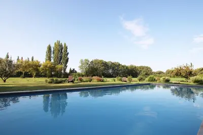 a large pool of blue water in a park at Le Jardin d'Érables St Remy 7 HA Piscine/Clim in Paluds de Noves