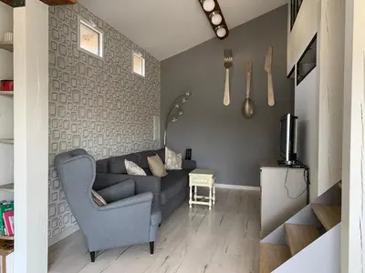 a living room with a gray couch and a tv at Clos du Cardinal in LʼIsle-sur-la-Sorgue
