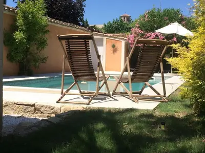 two lawn chairs sitting next to a swimming pool at Belle maison provençale au pied du Mont Ventoux in Caromb