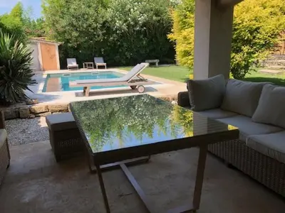 a living room with a table and a couch and a pool at Belle maison provençale au pied du Mont Ventoux in Caromb