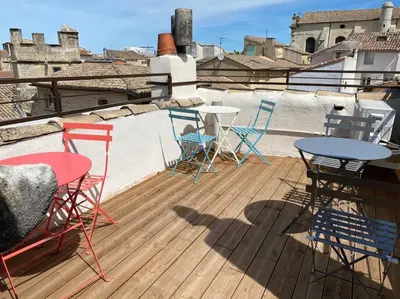 a deck with chairs and tables on a roof at La tour 2: Appart neuf au cœur de la petite venise in LʼIsle-sur-la-Sorgue