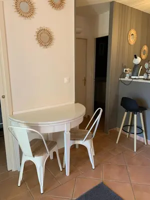 a white table and chairs in a kitchen with a counter at appartement cosy avec climatisation réversible GOLF DE SAUMANE in Saumane-de-Vaucluse