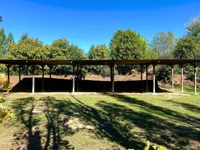 a wooden pavilion in a field with trees in the background at Domaine Plan des Devens in Roussillon