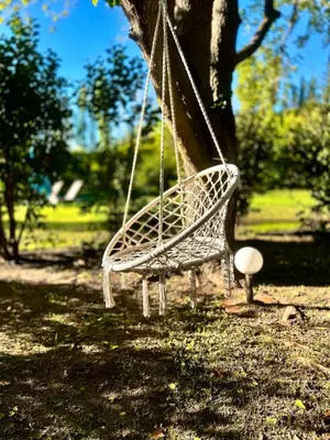 a white swing hanging from a tree in a park at Domaine Plan des Devens in Roussillon