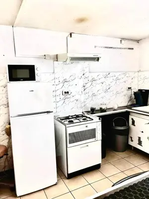 a white kitchen with a stove and a refrigerator at Appartement charmant à Avignon - 50 m² - Terrasse privée in Avignon