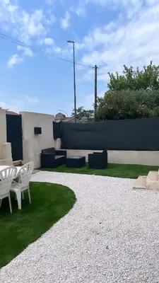 a patio with two white chairs and green grass at Logement privé à proximité du Mont Ventoux in Carpentras