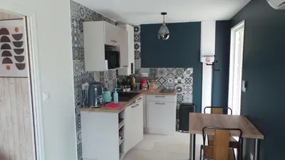 a kitchen with blue walls and a wooden table at Le Nid'Isle - Stationnement privé gratuit - Wi-Fi performant - Climatisation in LʼIsle-sur-la-Sorgue