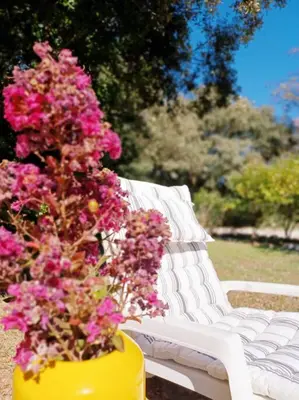 a yellow vase filled with pink flowers next to a white bench at Bastide Cedrea in Peyrolles-en-Provence