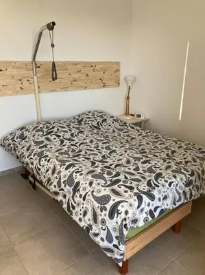 a bed with a black and white comforter in a bedroom at Appartement RDC avec parking privé in La Fare-les-Oliviers