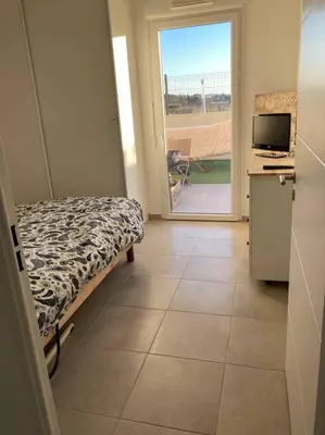 a room with a bed and a television on a tiled floor at Appartement RDC avec parking privé in La Fare-les-Oliviers