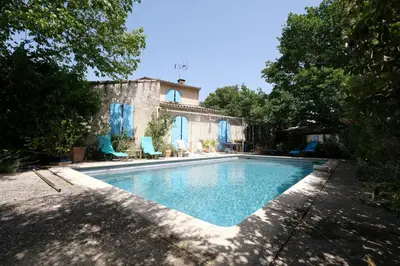 a swimming pool in front of a house at jolie location, maison avec piscine et joli jardin fleuri, à oppède dans le luberon en provence – 6 personnes in Oppède