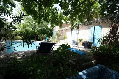 a swimming pool with two blue chairs in a yard at jolie location, maison avec piscine et joli jardin fleuri, à oppède dans le luberon en provence – 6 personnes in Oppède