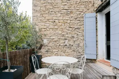 a table and chairs on a patio with a stone wall at appartement de charme dans le luberon in Lagnes