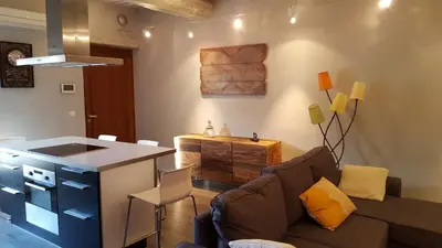 a living room with a couch and a table and a kitchen at appartement de charme dans le luberon in Lagnes