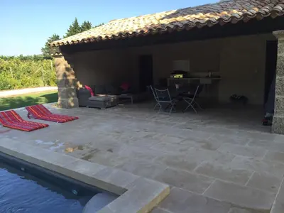 a patio with a table and chairs next to a pool at MAS DE CHARME EN PROVENCE in Le Thor