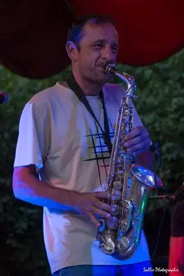 a man is playing a saxophone on a stage at Sous un chêne bicentenaire in Lambesc